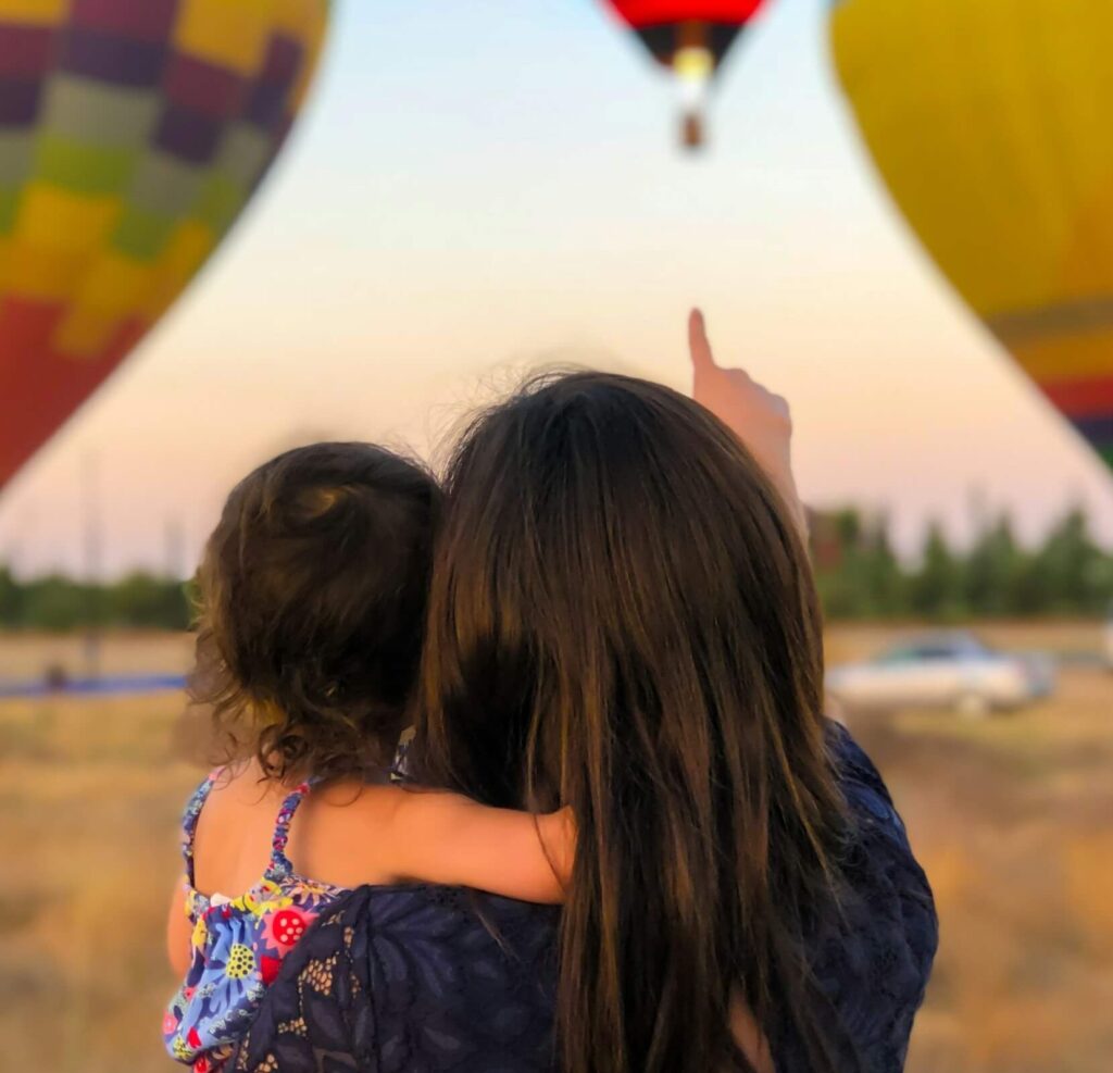 子どもを抱いて空を見上げる母親の後ろ姿。未来を見つめながら、健康への意識を表す写真
